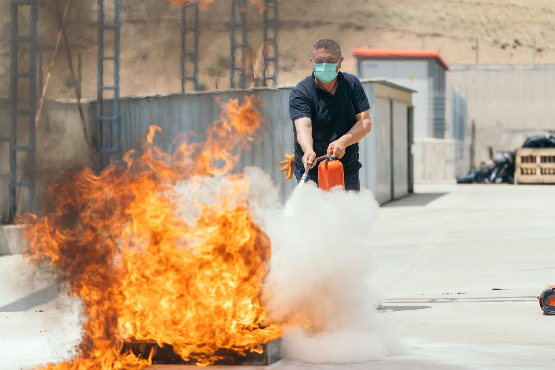 A man wearing a mask is using a fire extinguisher to put out a fire.