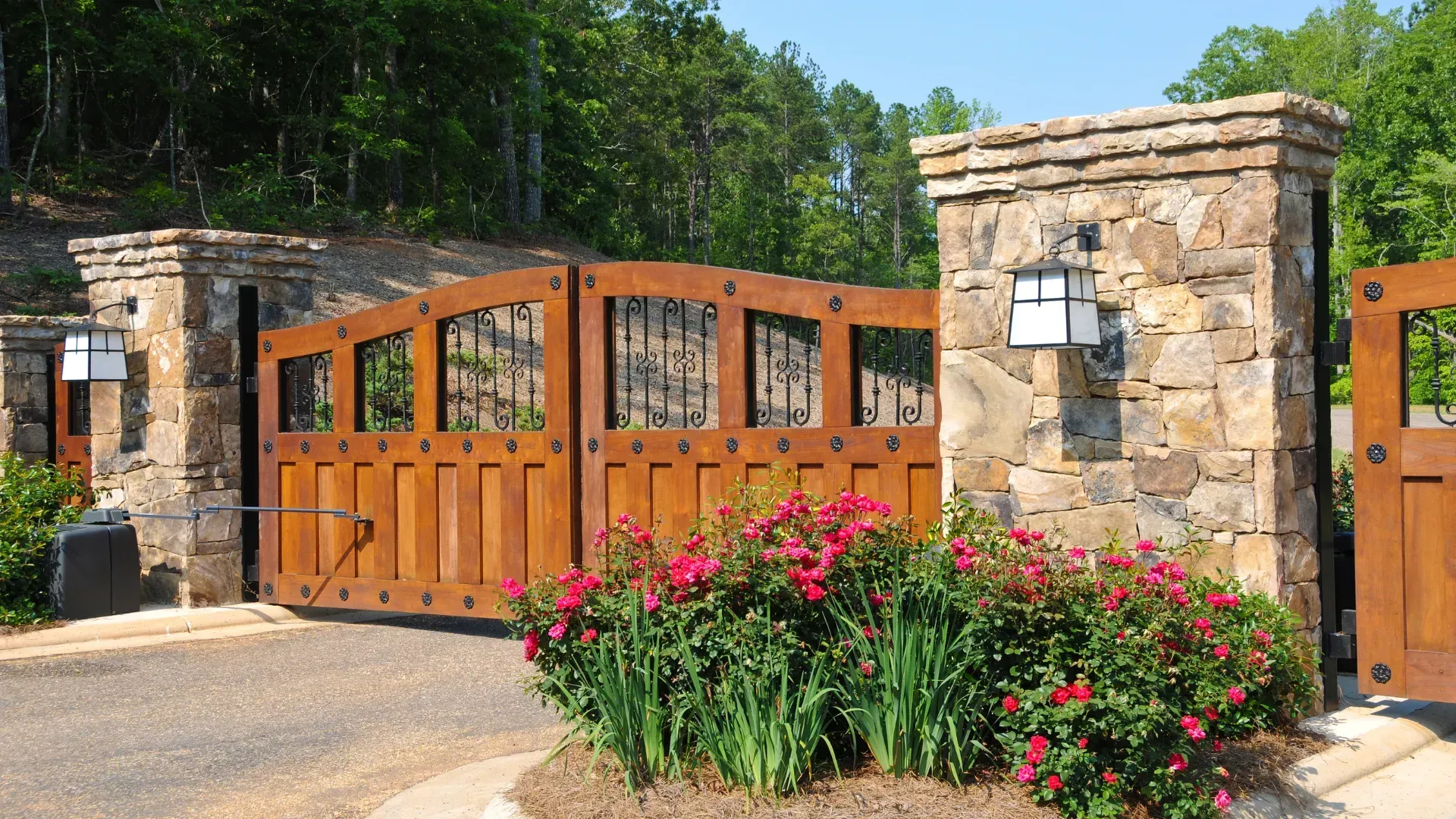 Wooden gate between stone pillars with red roses.