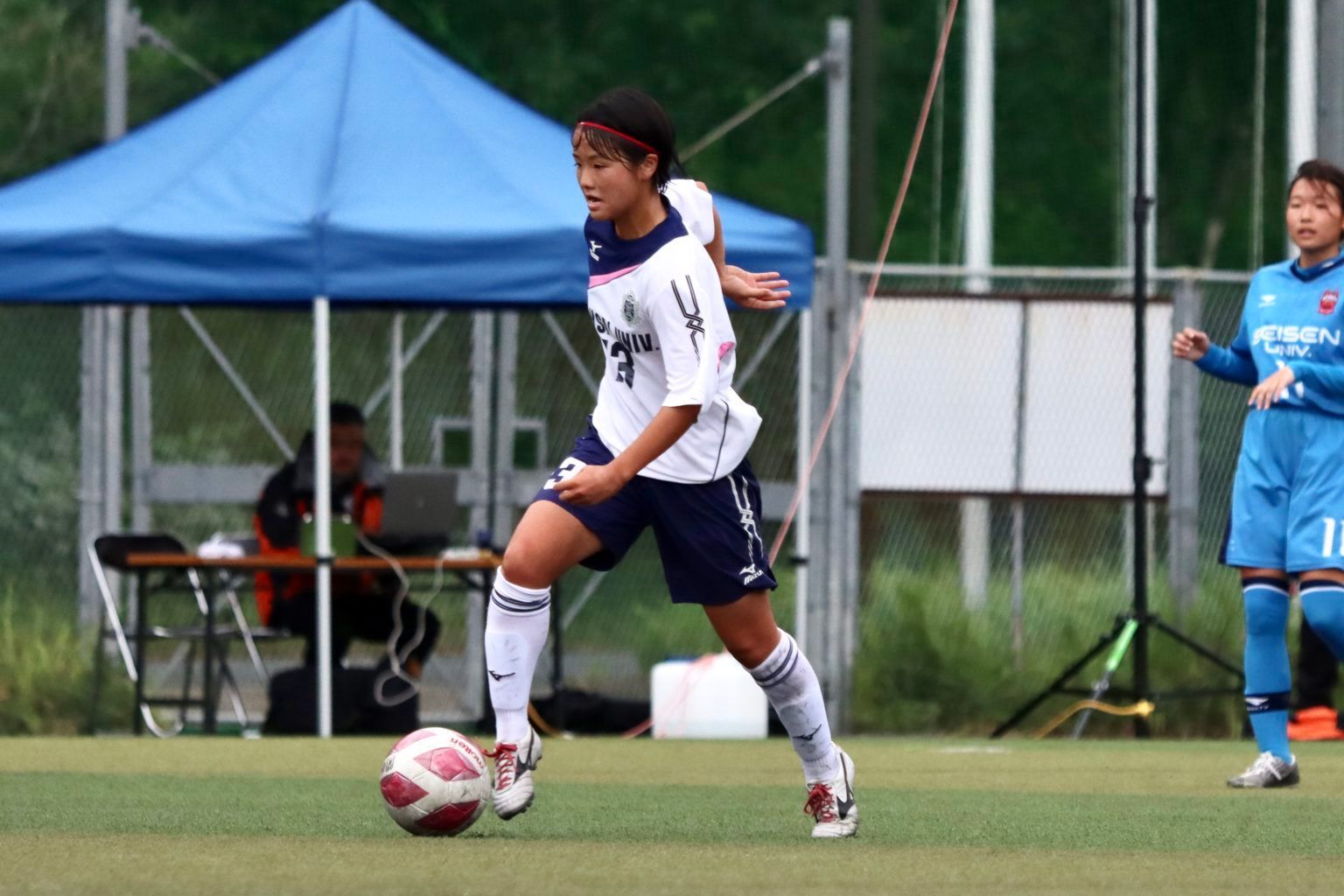A soccer player in a white shirt is kicking a ball