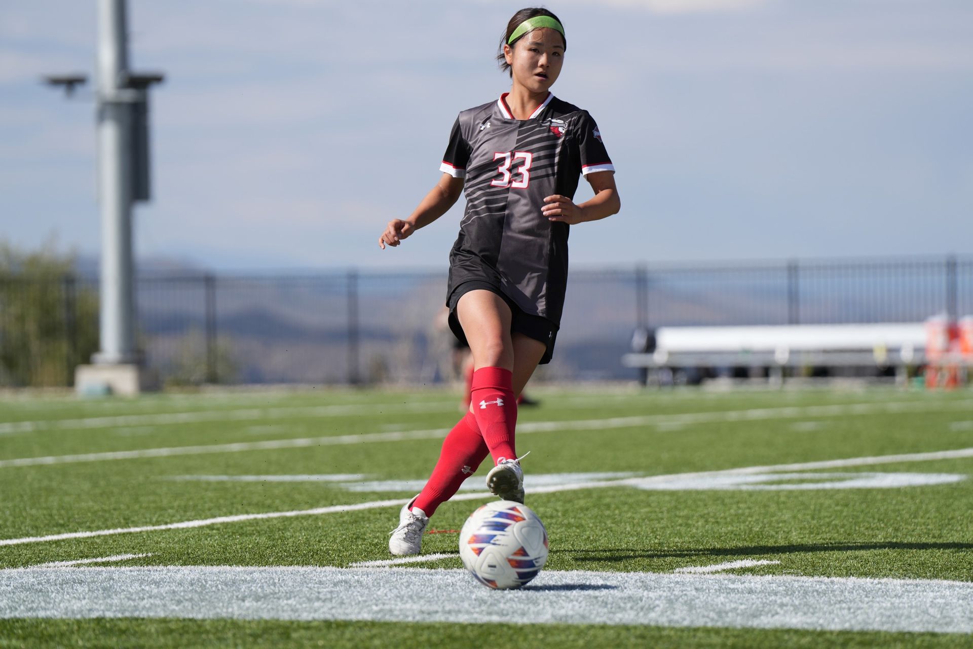 A girl is kicking a soccer ball on a field.