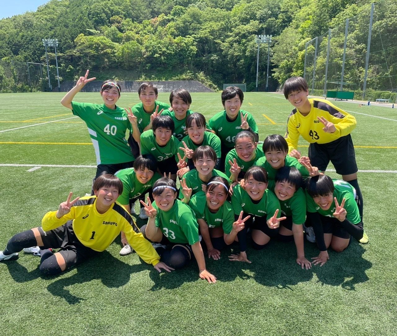 A group of young girls are posing for a picture on a soccer field.