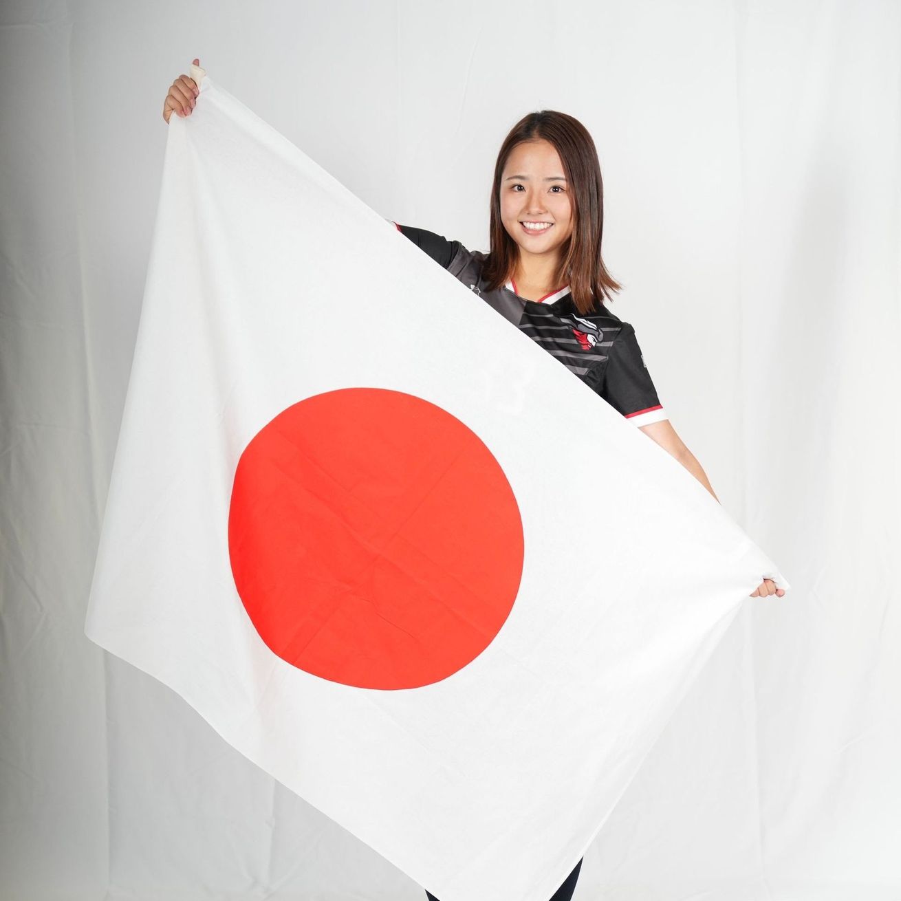 A woman is holding a large white flag with a red circle in the middle