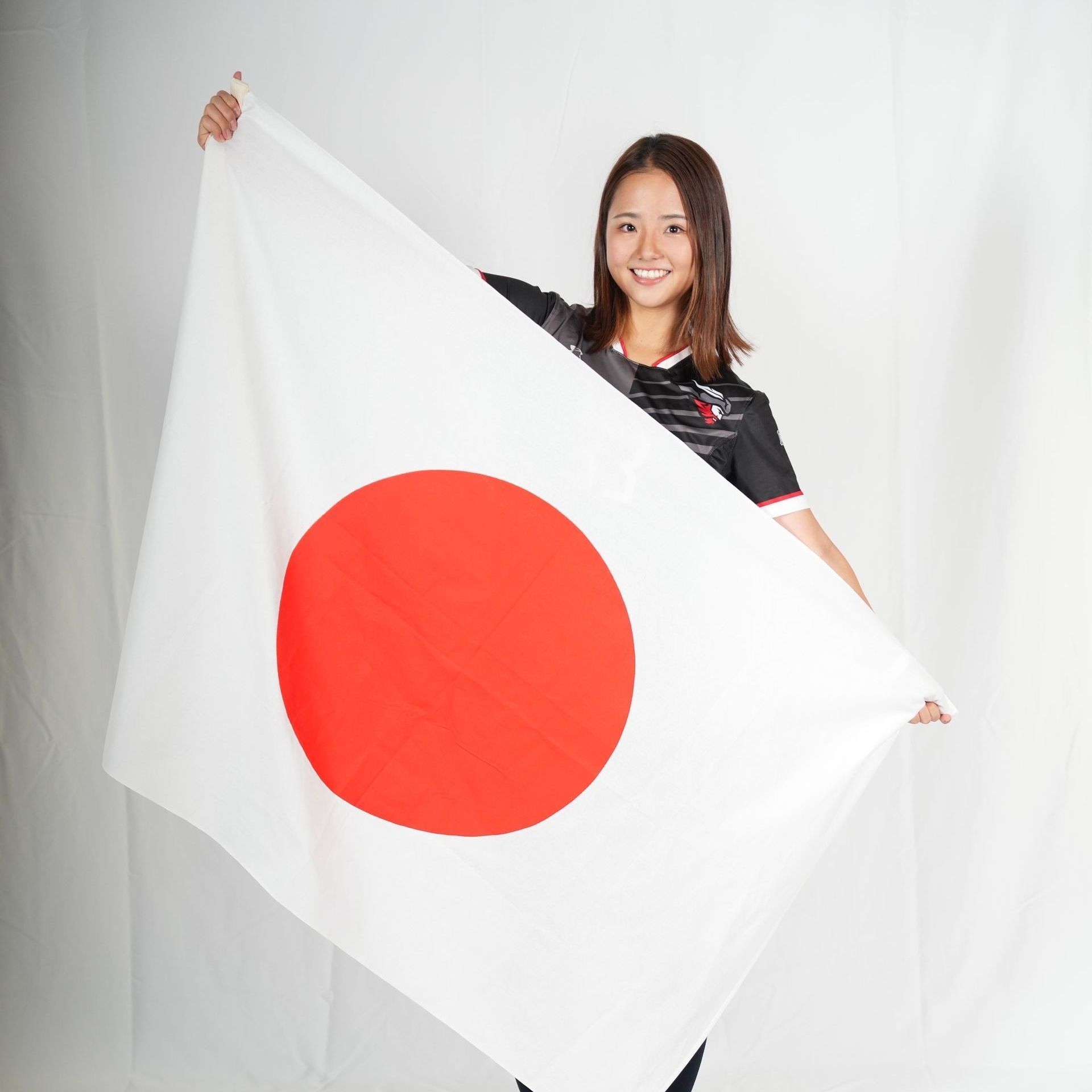 A woman is holding a large white flag with a red circle in the middle