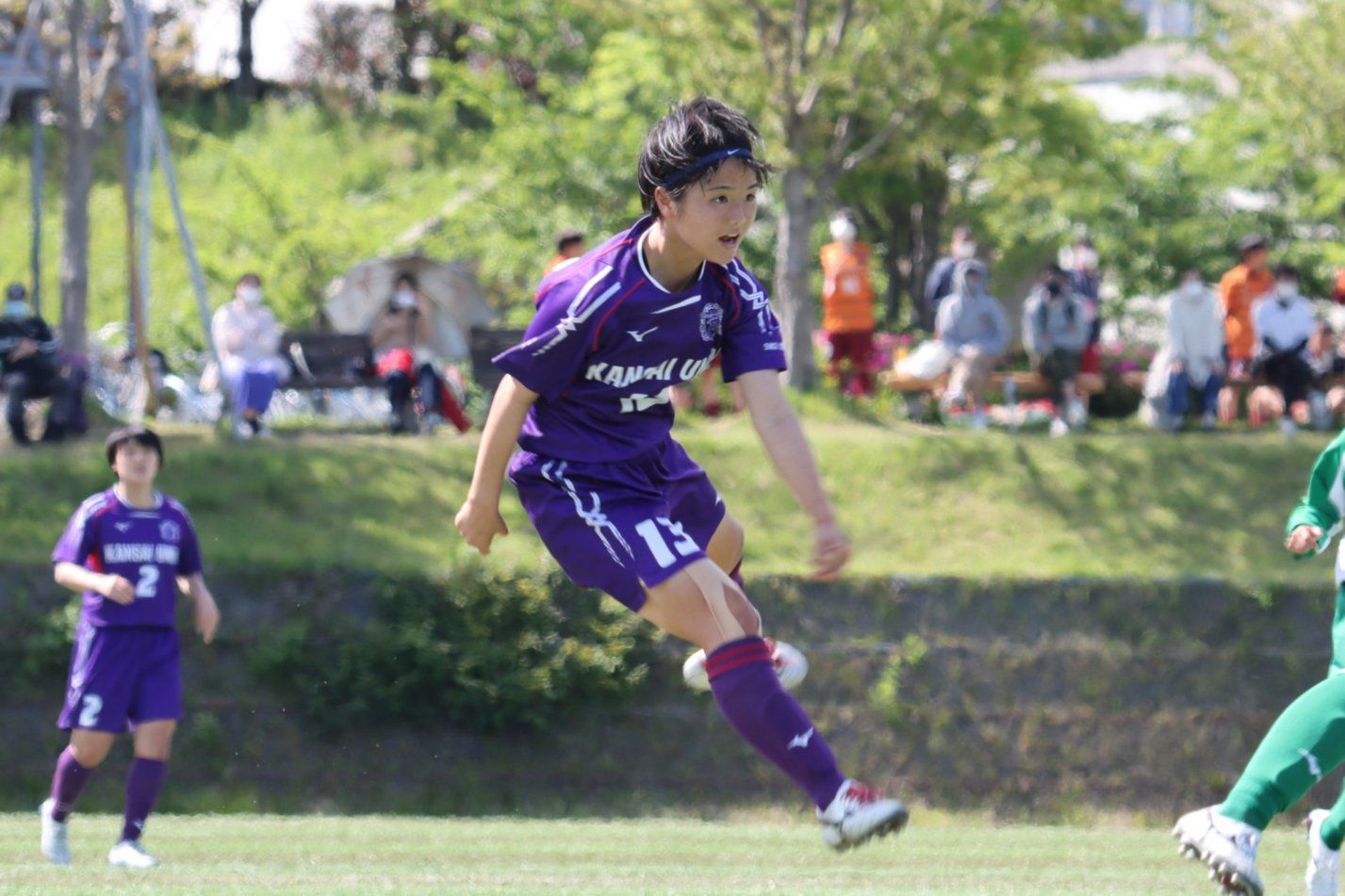 A female soccer player is jumping in the air while playing soccer on a field.