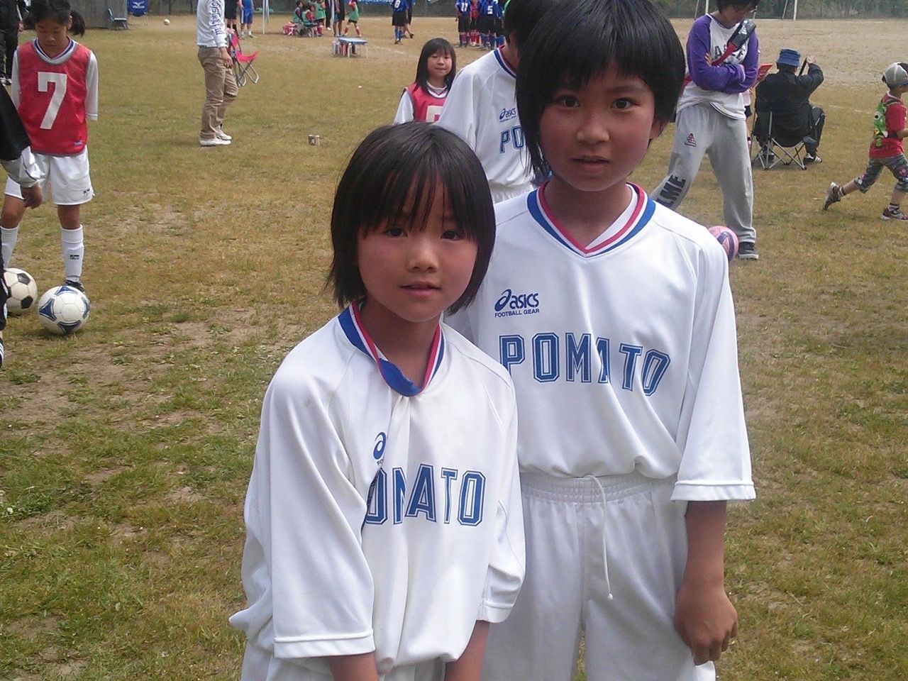 Two young girls wearing pomuto jerseys pose for a picture