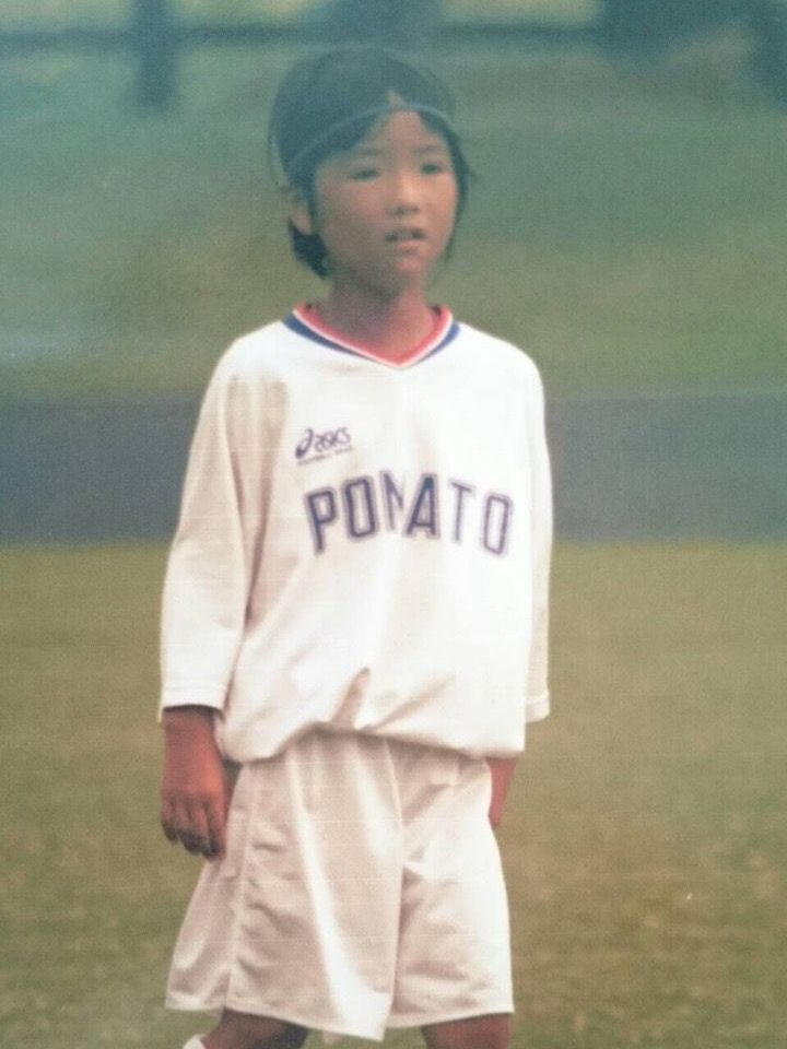 A young boy wearing a potato jersey stands on a field