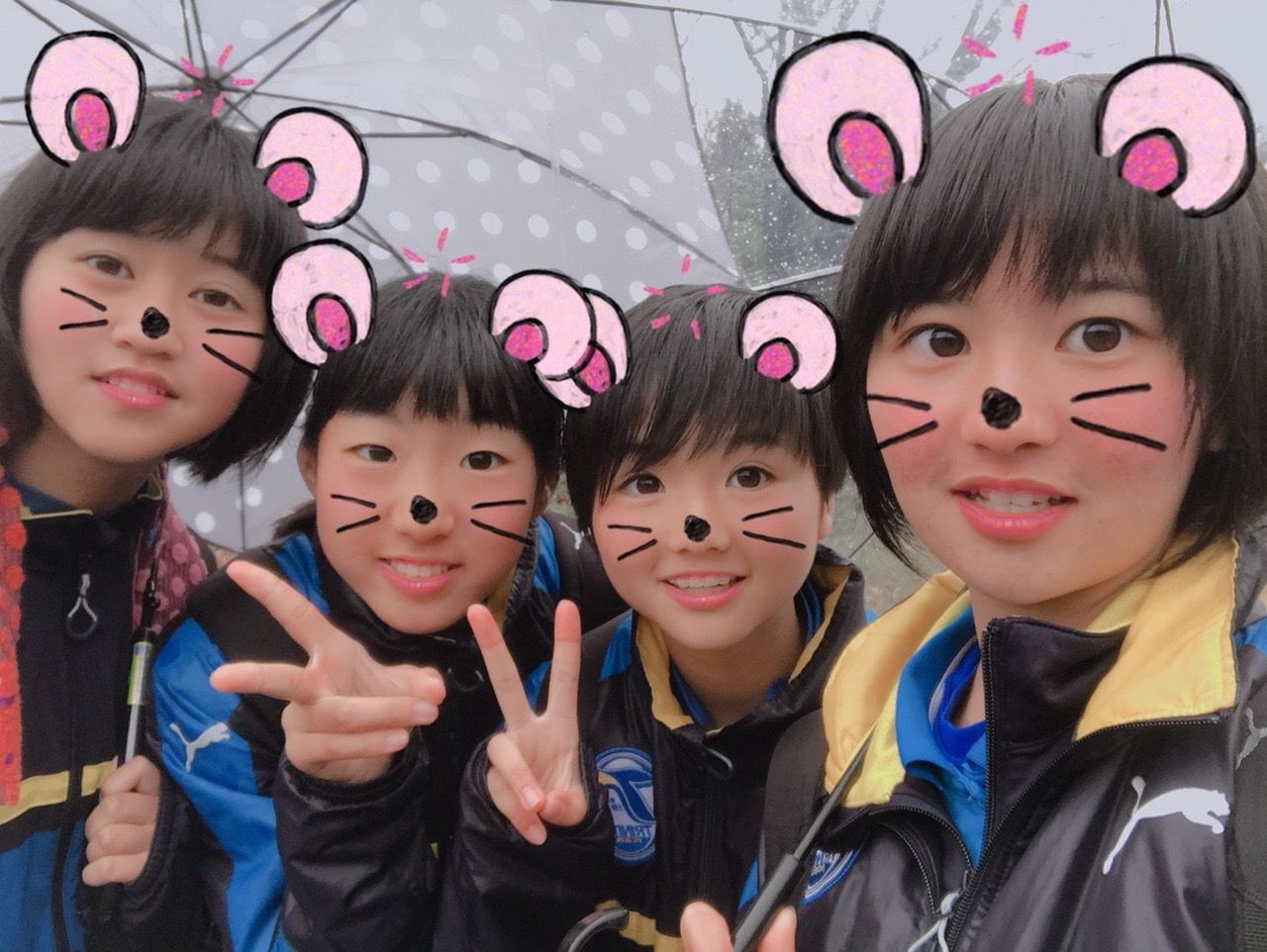 A group of young girls are posing for a picture in the rain.