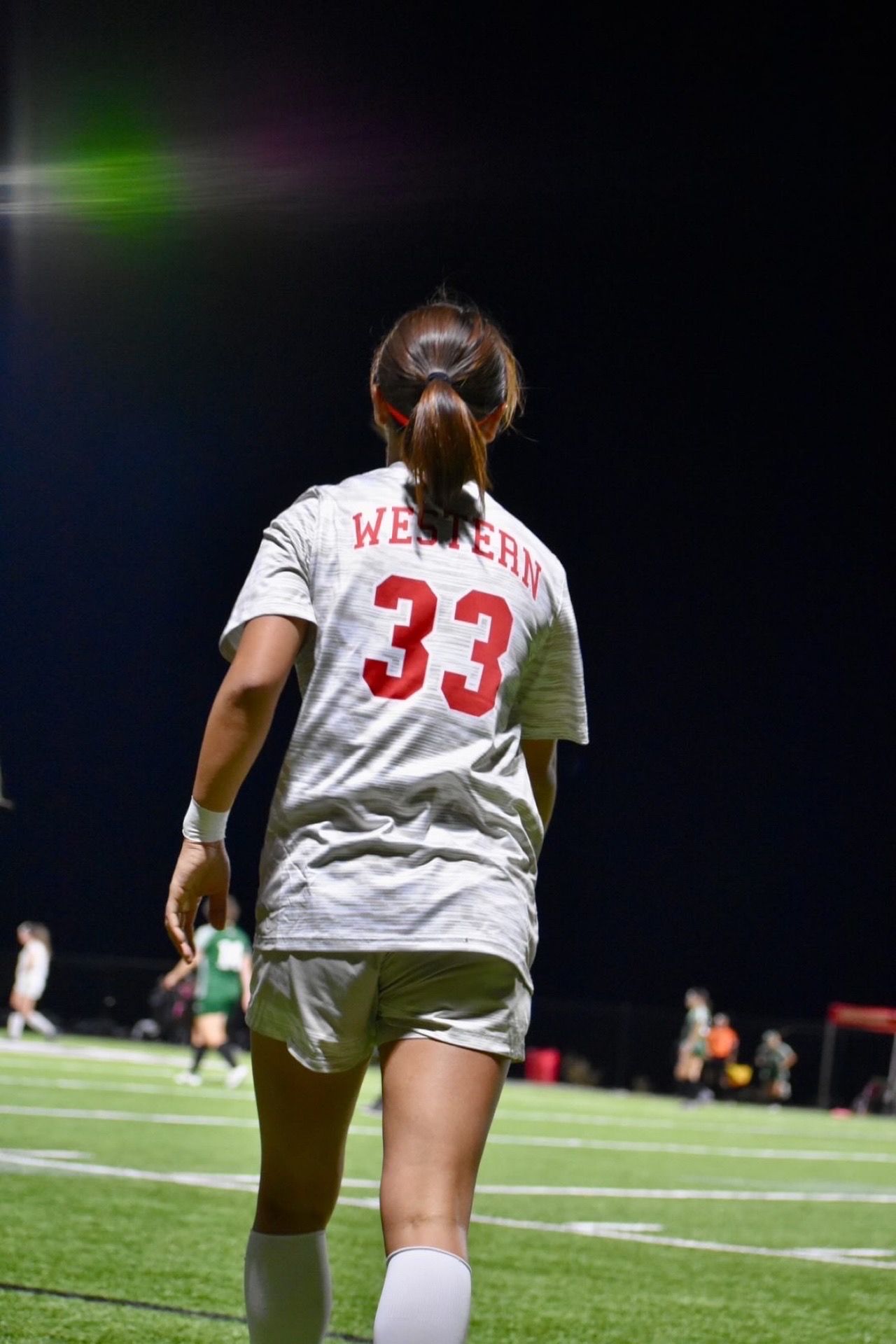 A female soccer player wearing a number 33 jersey is walking on a field.