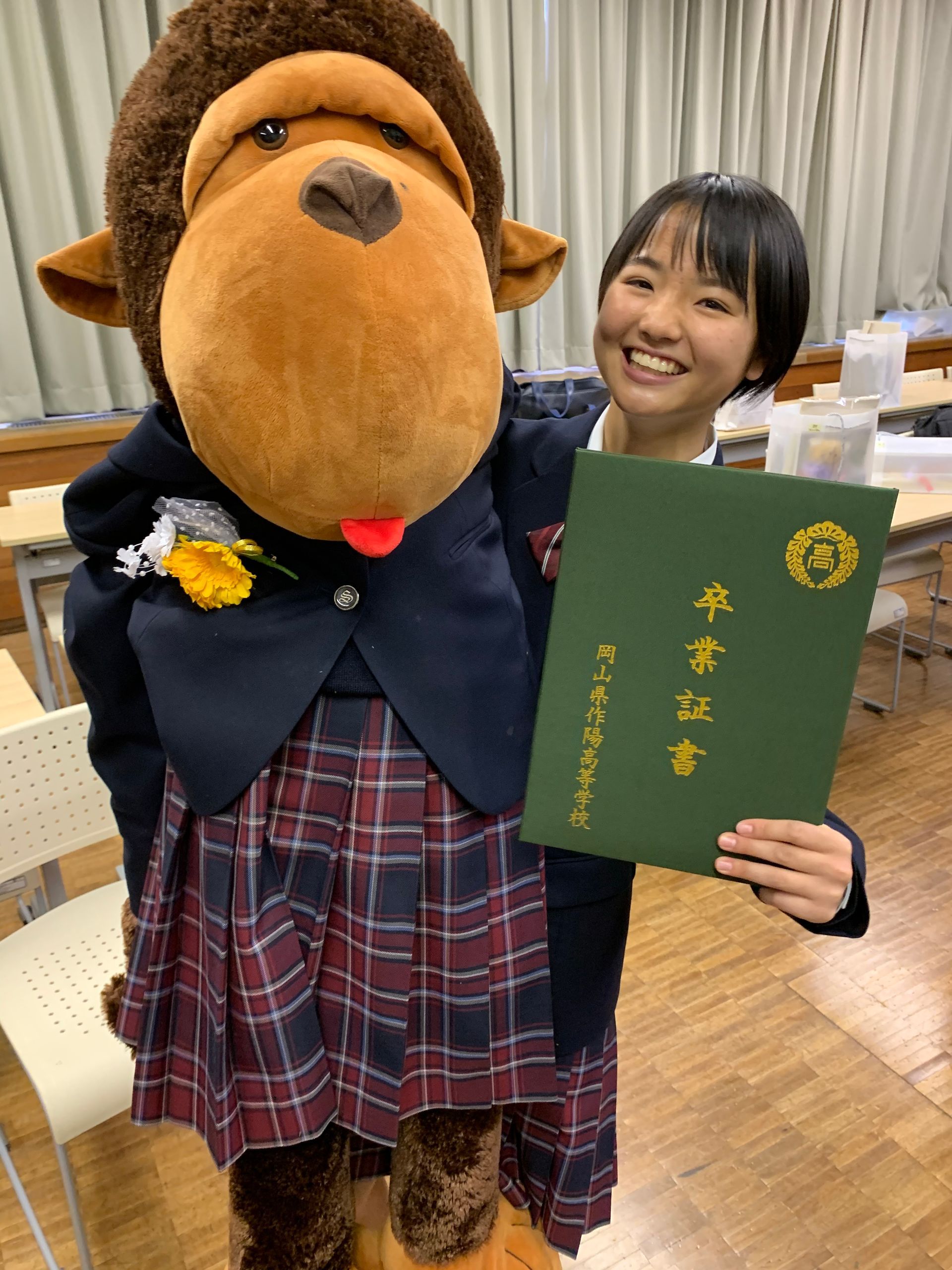 A girl is holding a diploma next to a stuffed monkey.