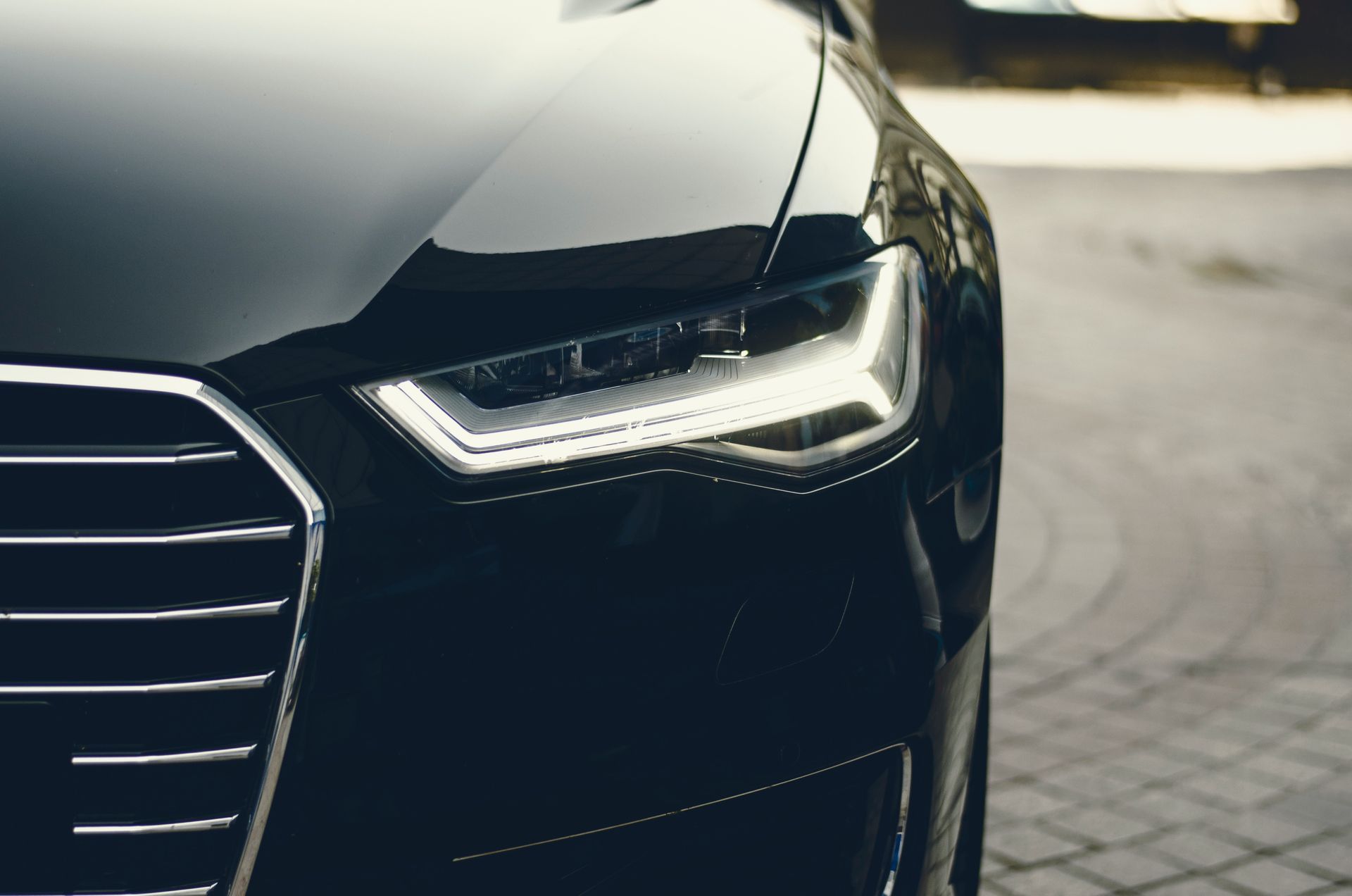 A close up of a black car parked on a cobblestone street.