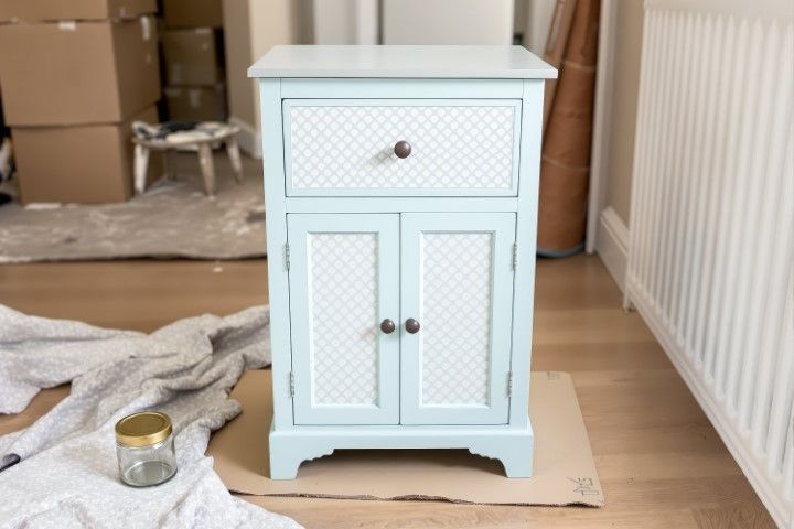 Light blue nightstand with a drawer and cabinet doors, on a wood floor.