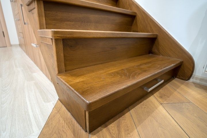 Wooden stairs with built-in drawers, side panel, and light wood flooring.