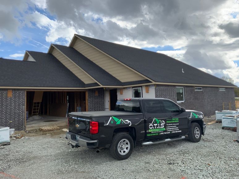 A black truck is parked in front of a house under construction.