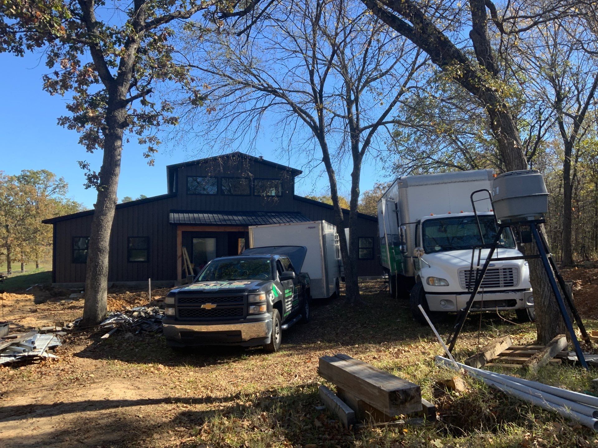 Two trucks are parked in front of a house under construction.