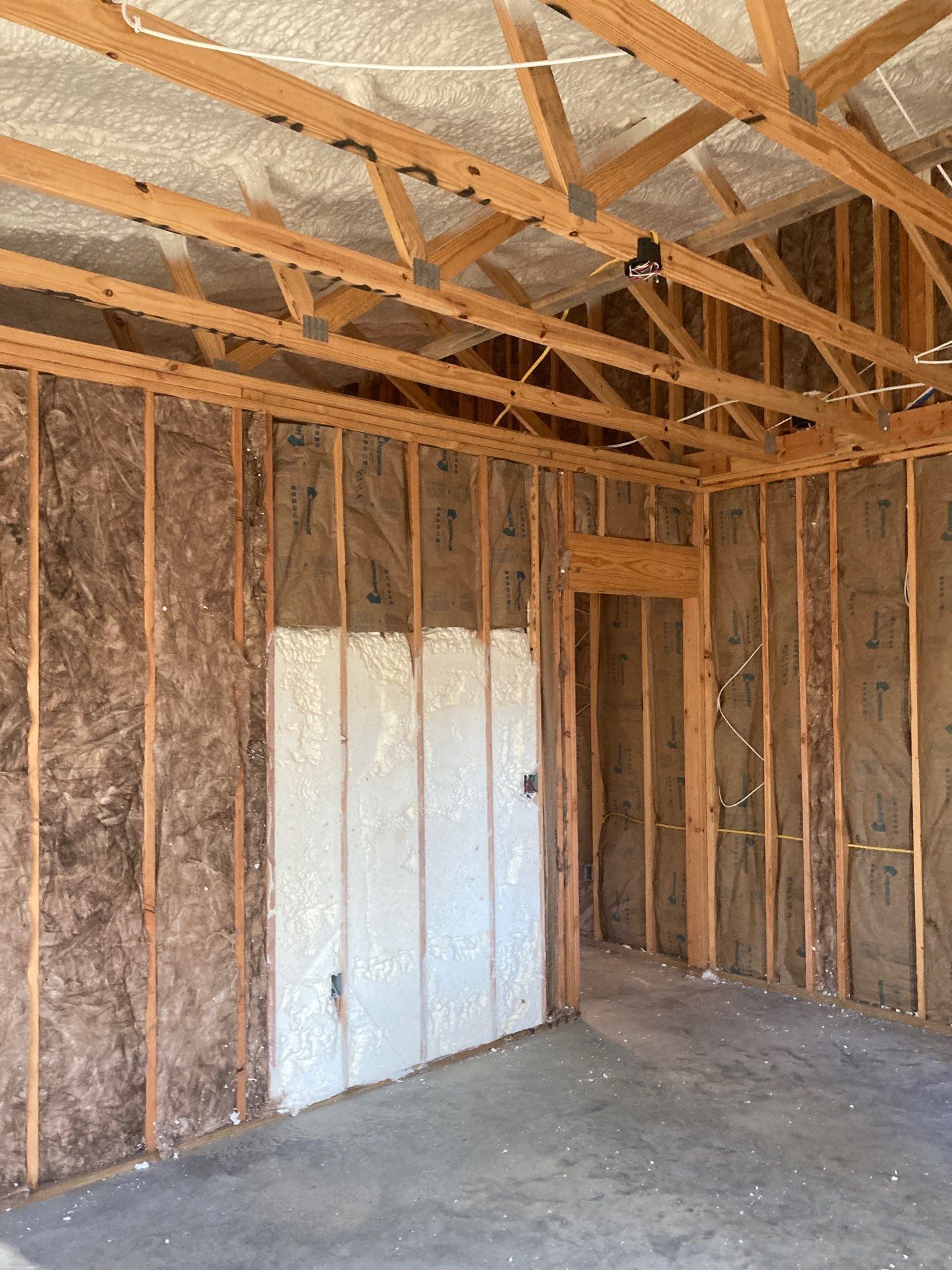 An empty room with wooden beams and insulation on the walls.