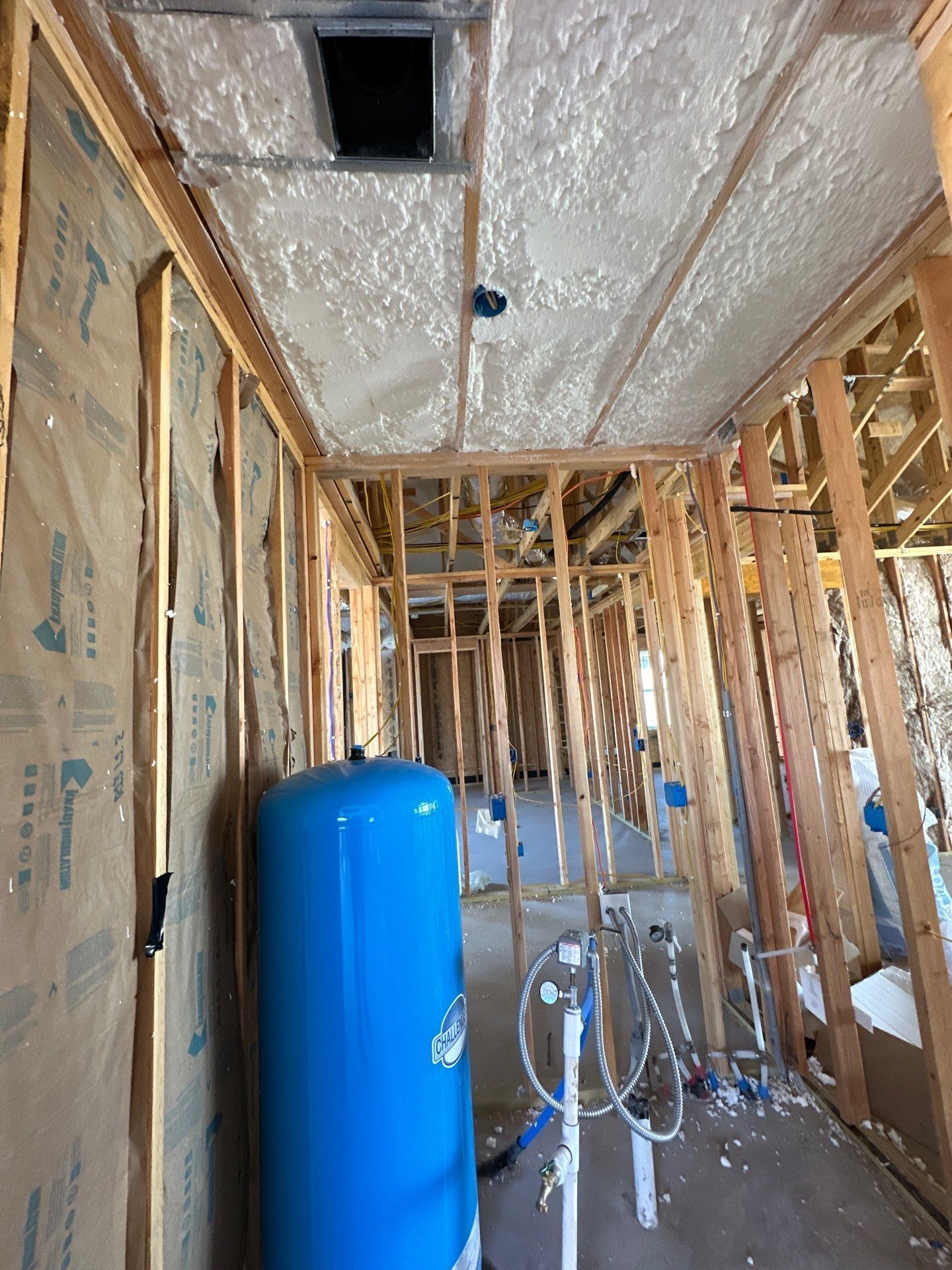 A blue water tank is sitting in the middle of a room in a house under construction.
