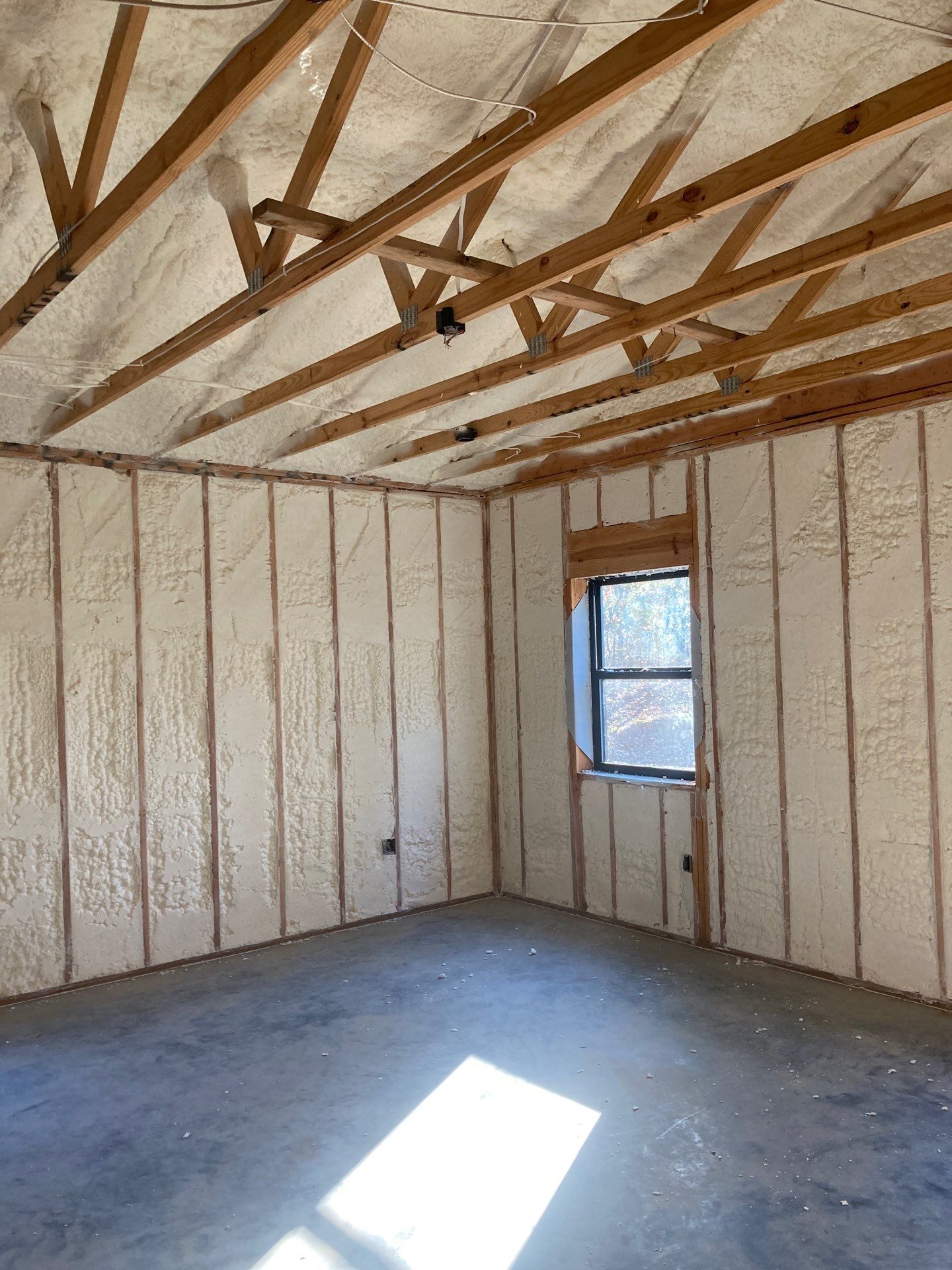 A room with foam insulation on the walls and ceiling and a window.