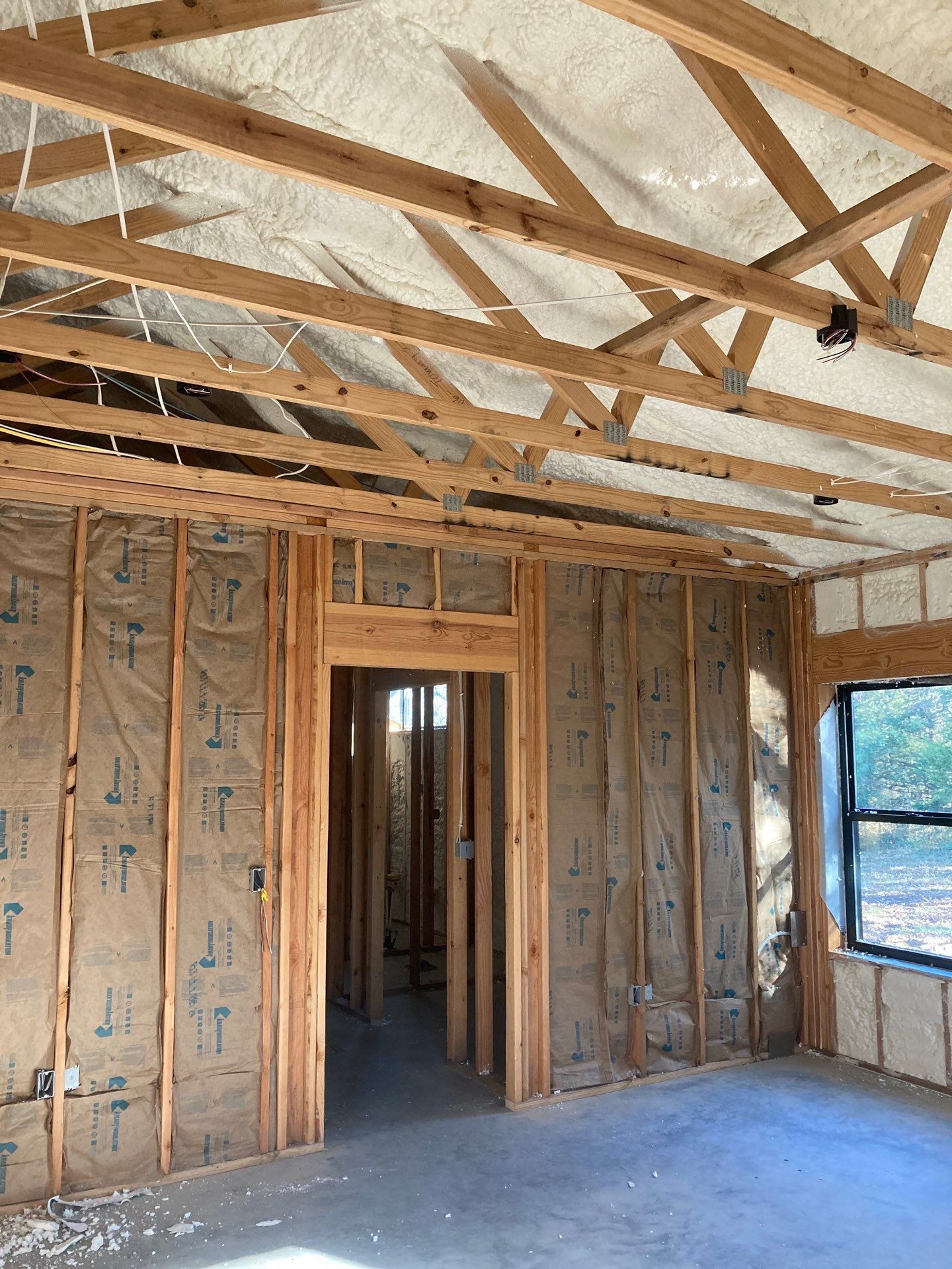 A room in a house under construction with wooden beams and insulation.