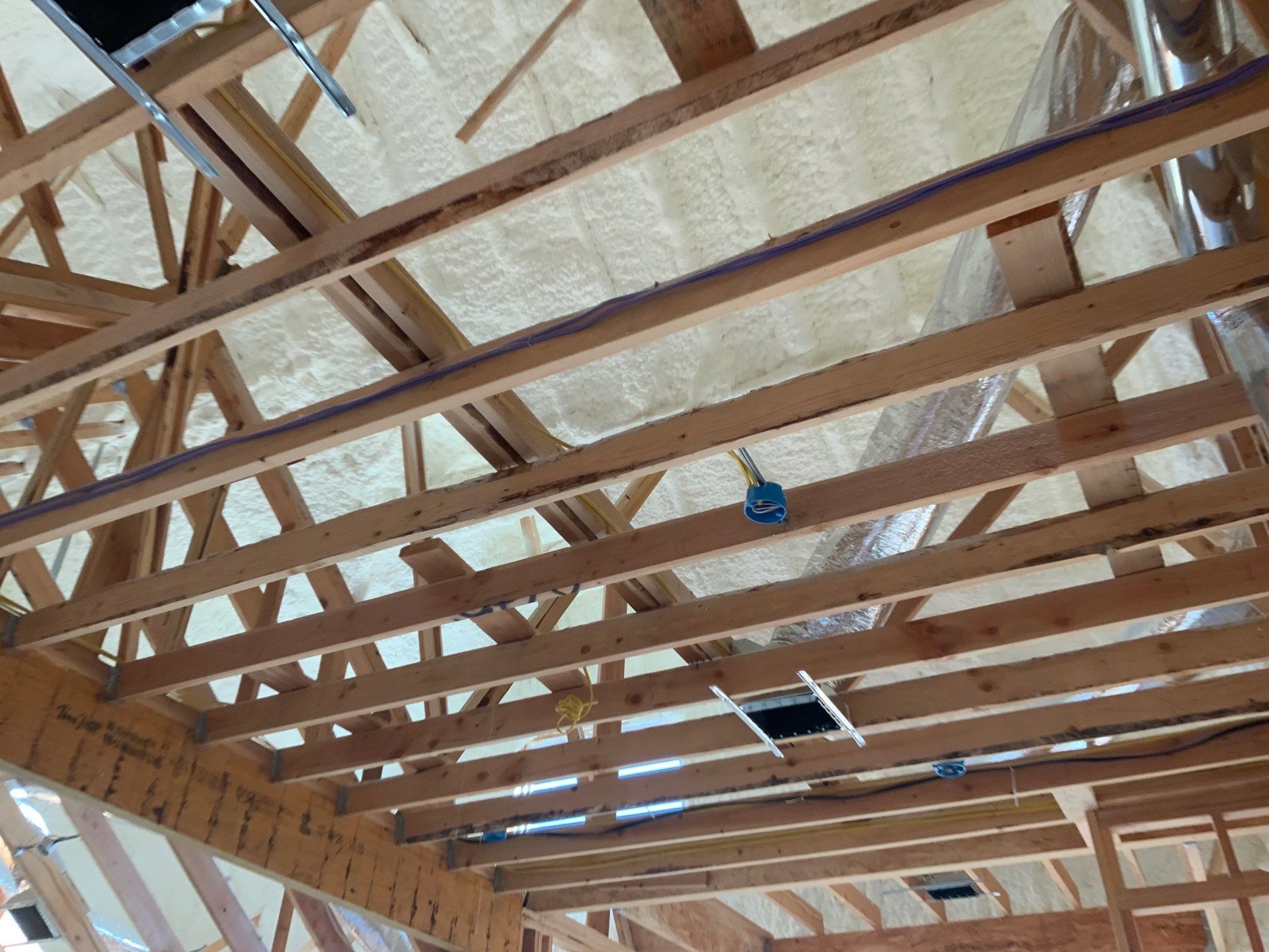 The ceiling of a building under construction with a lot of wooden beams.