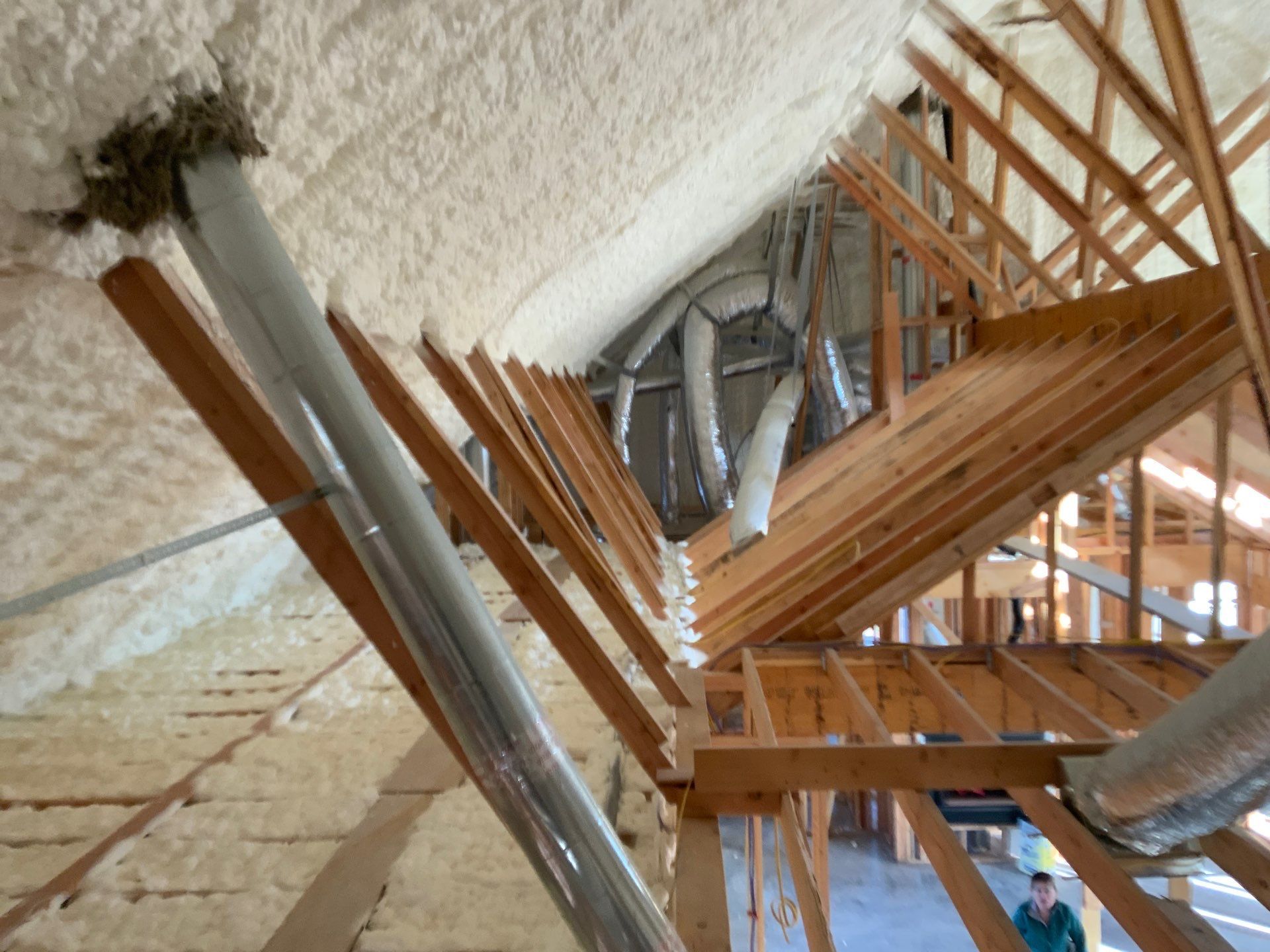 A man is standing in the attic of a building under construction