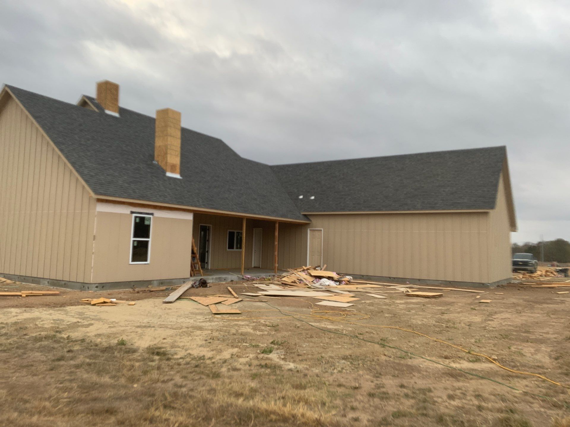 A house with a black roof is being built in a field
