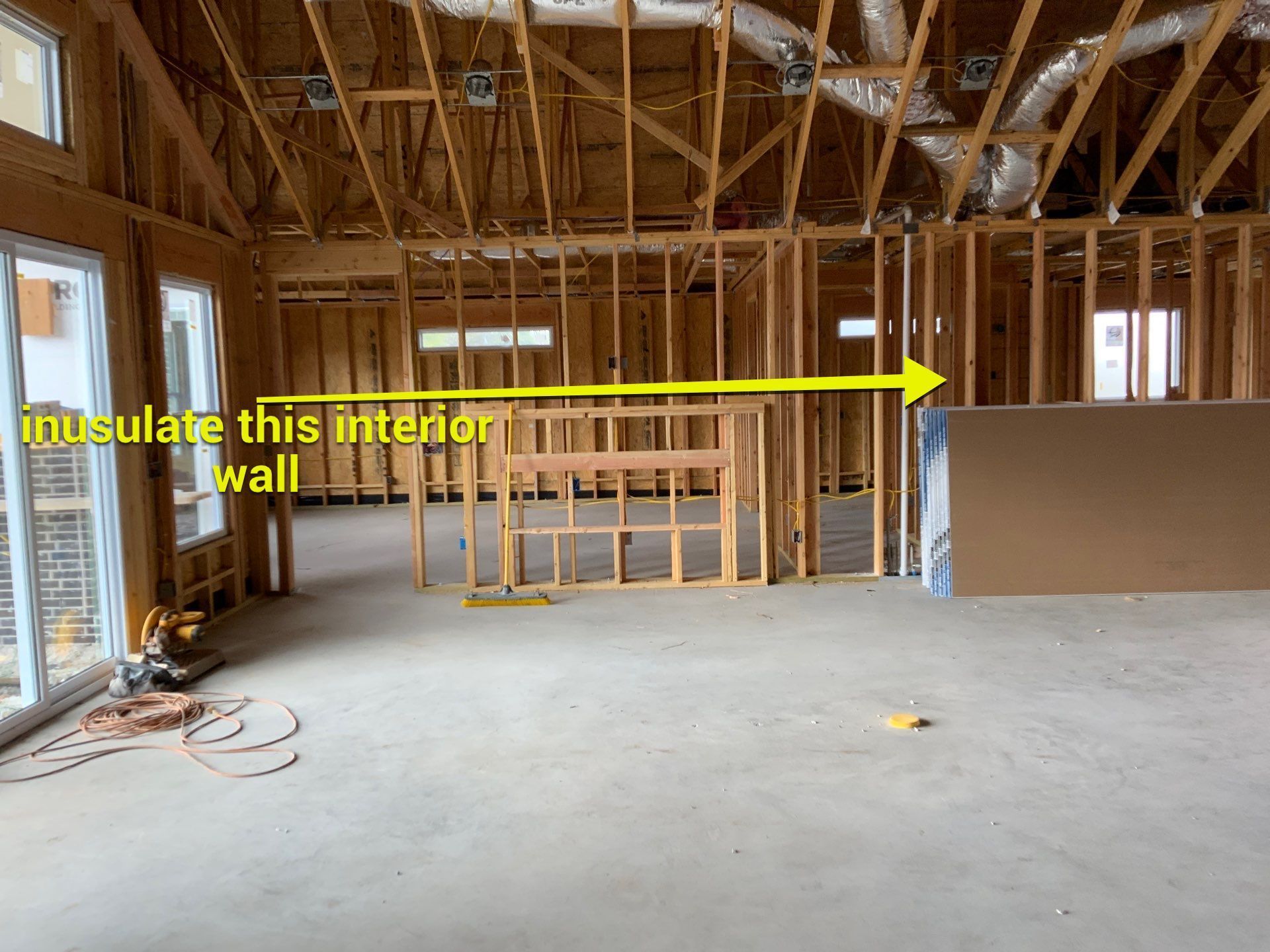 A picture of a house under construction with a yellow arrow pointing to the interior wall.