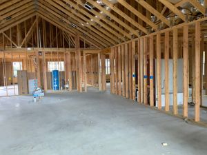 The inside of a building under construction with wooden beams and a concrete floor.