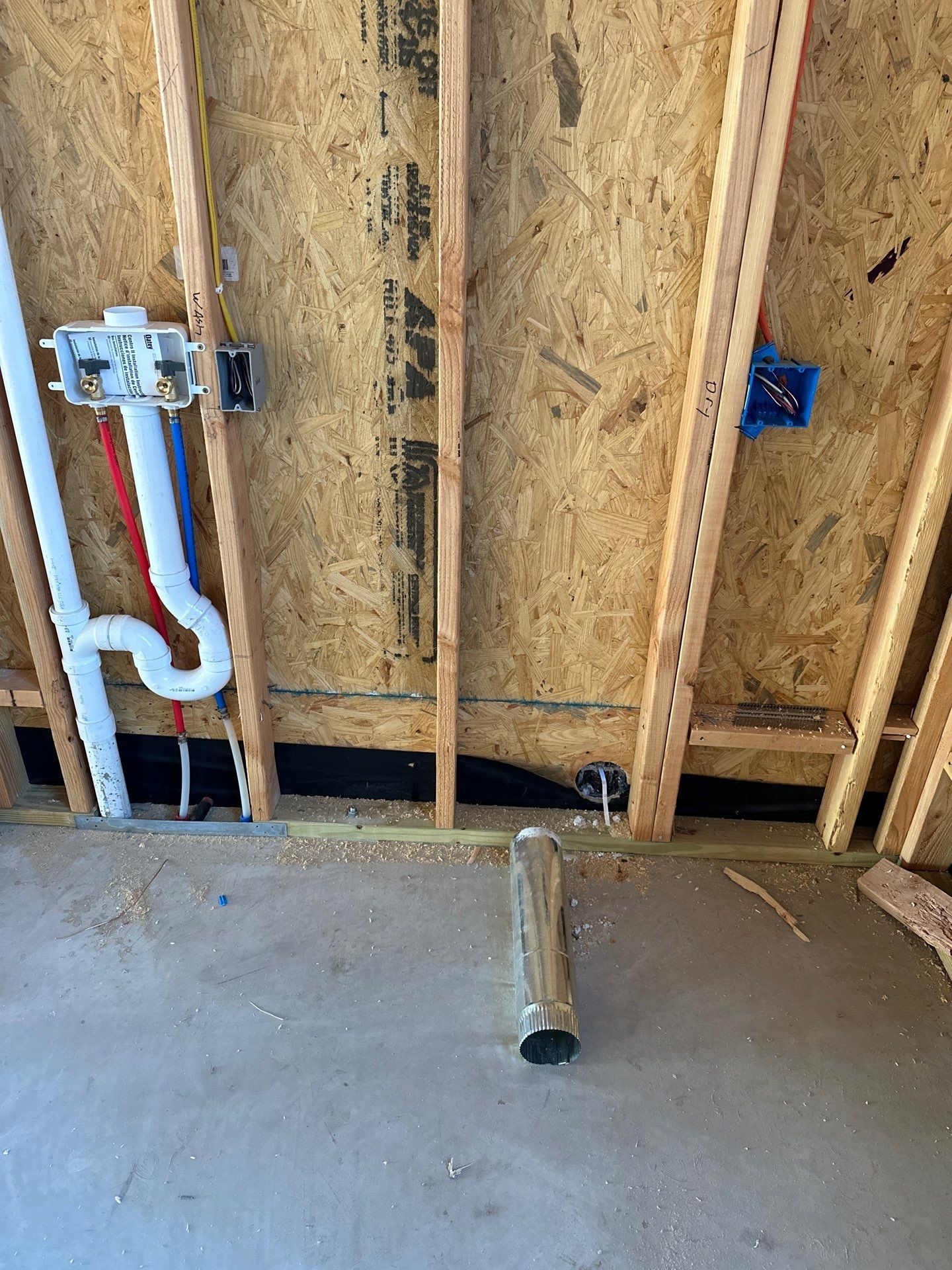 A bathroom under construction with pipes coming out of the wall.