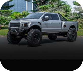 White car raised on a red car lift in a garage, mechanic working underneath.