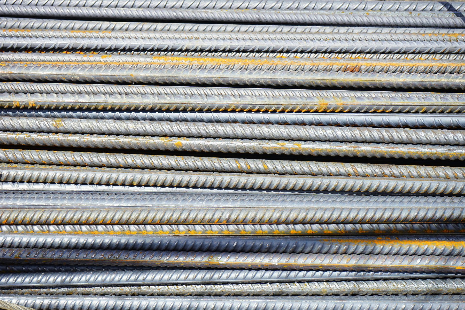 Close-up view of a stack of steel rebar rods with textured surfaces and some rust.