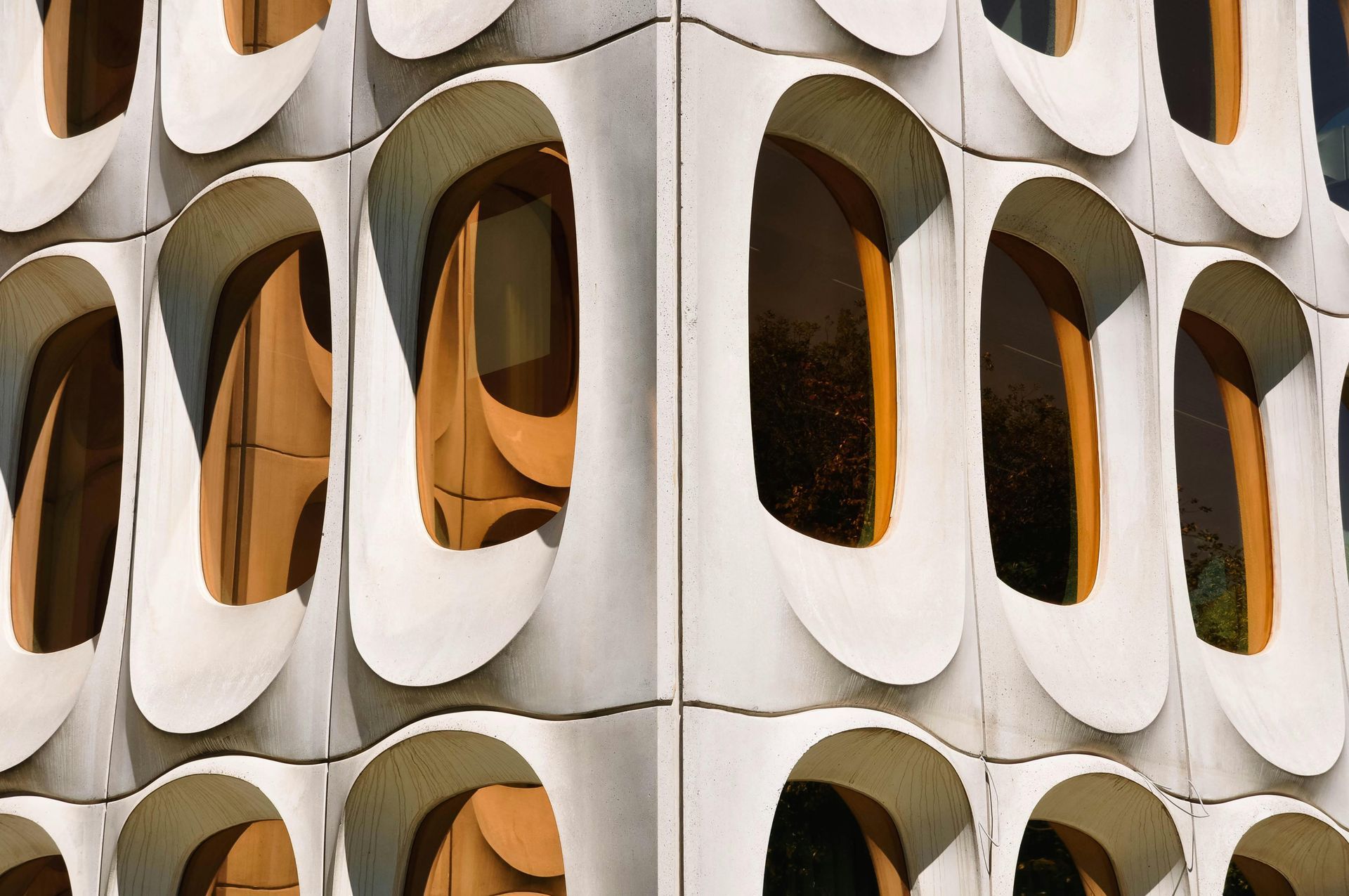 Exterior of a building with repeating, pod-shaped windows in a white concrete facade.