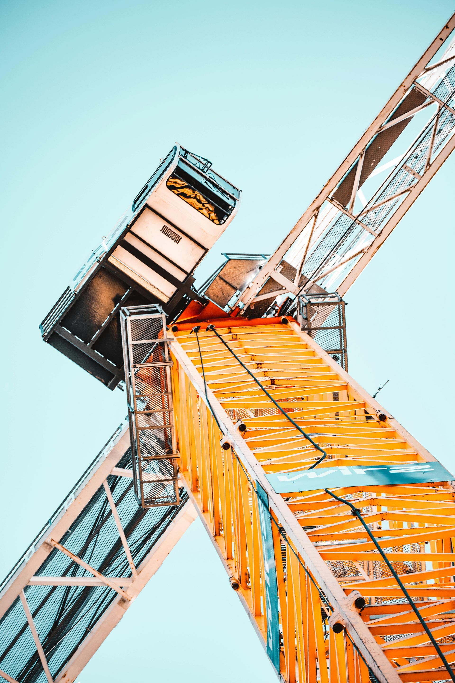 Giant amusement park ride with orange and white supports against a light blue sky.