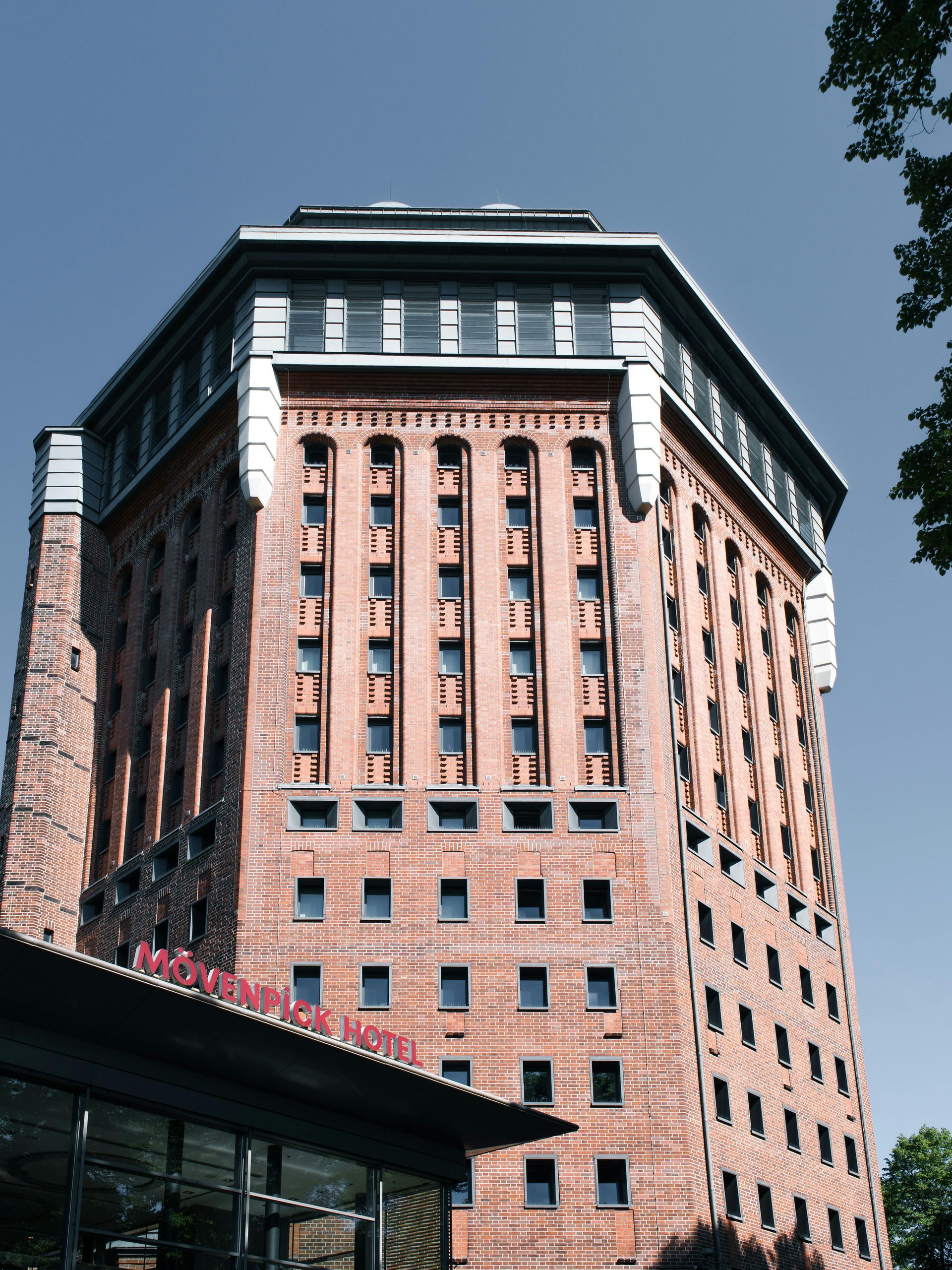 Red brick octagonal tower building with small square windows, under a clear blue sky.