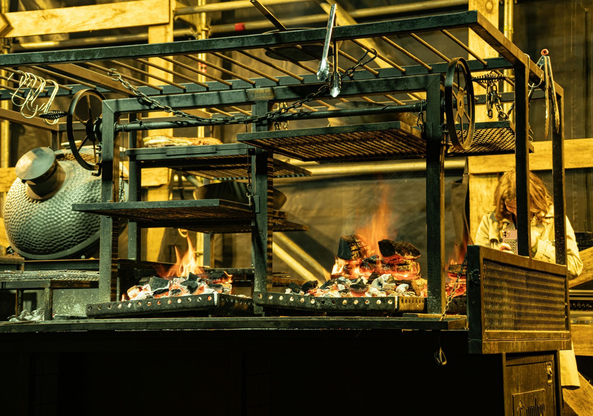 Large outdoor grilling setup with open flames and metal racks, possibly used in a restaurant.