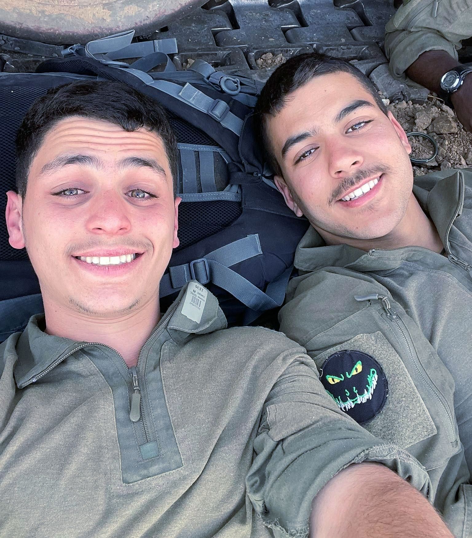 Two young men in military uniforms are smiling for a picture