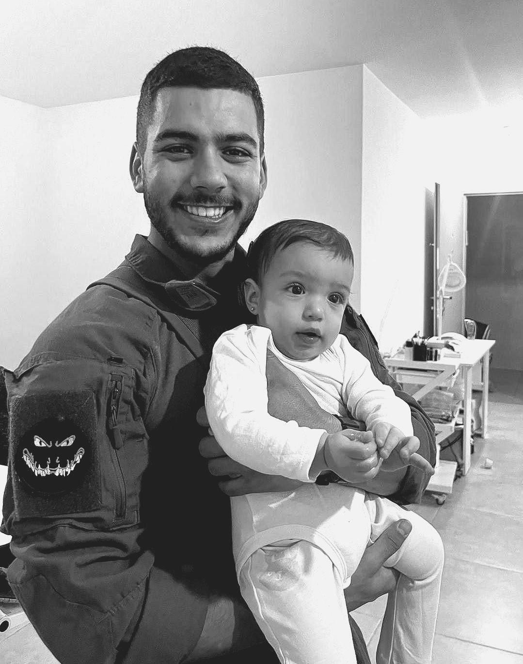 A man is holding a baby in his arms in a black and white photo.