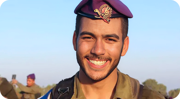 A man in a military uniform is smiling and wearing a purple hat.