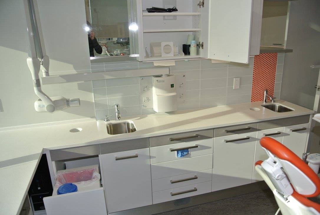 Une cuisine avec des armoires blanches, un évier et un miroir.