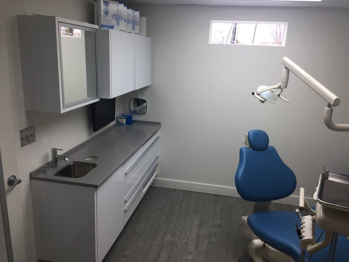 Un cabinet dentaire avec une chaise bleue et un lavabo