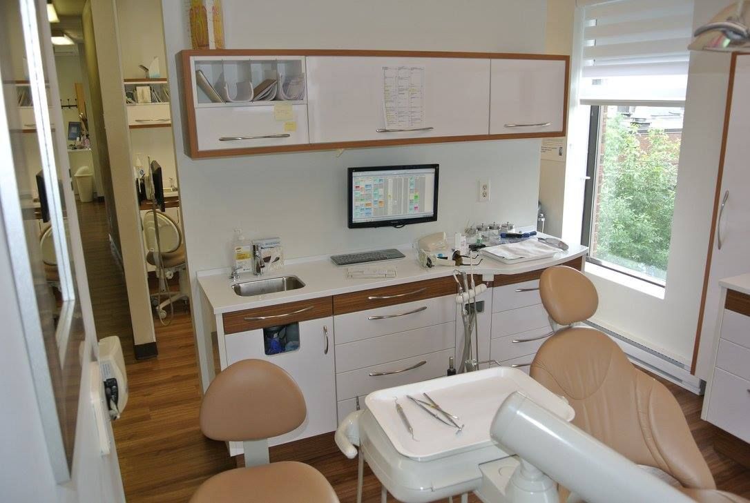 Un cabinet dentaire avec une chaise et un moniteur au mur