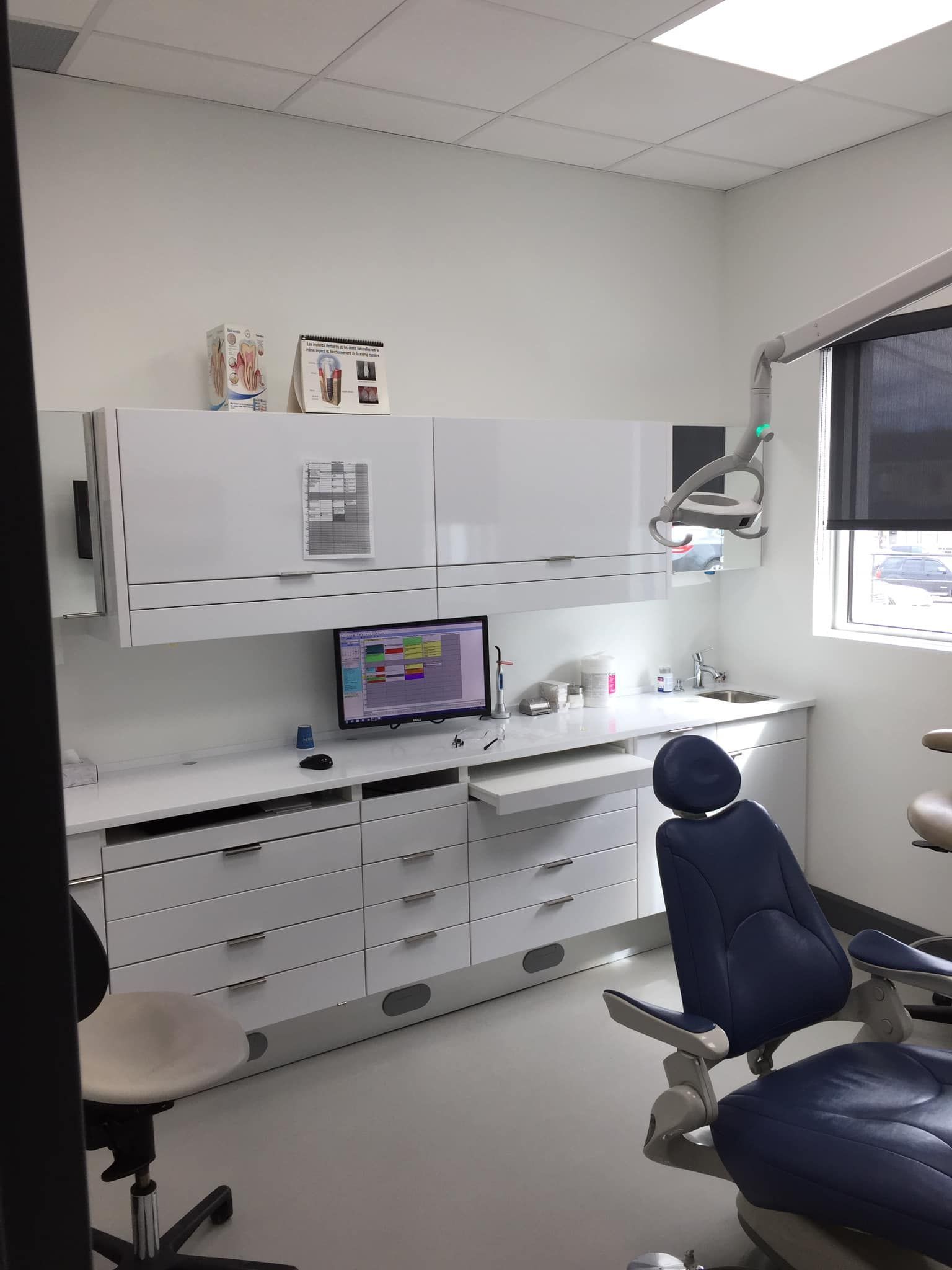 Un cabinet dentaire avec une chaise bleue et un ordinateur