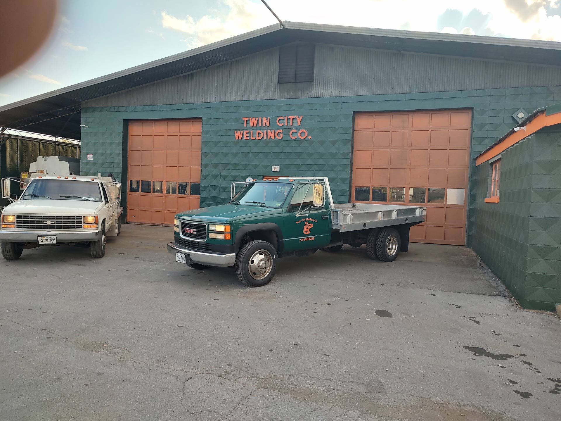 A green truck is parked in front of a building.