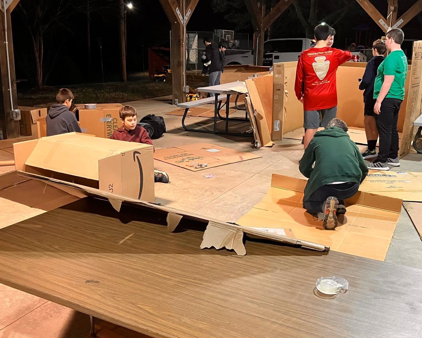 A group of children are playing with cardboard boxes.