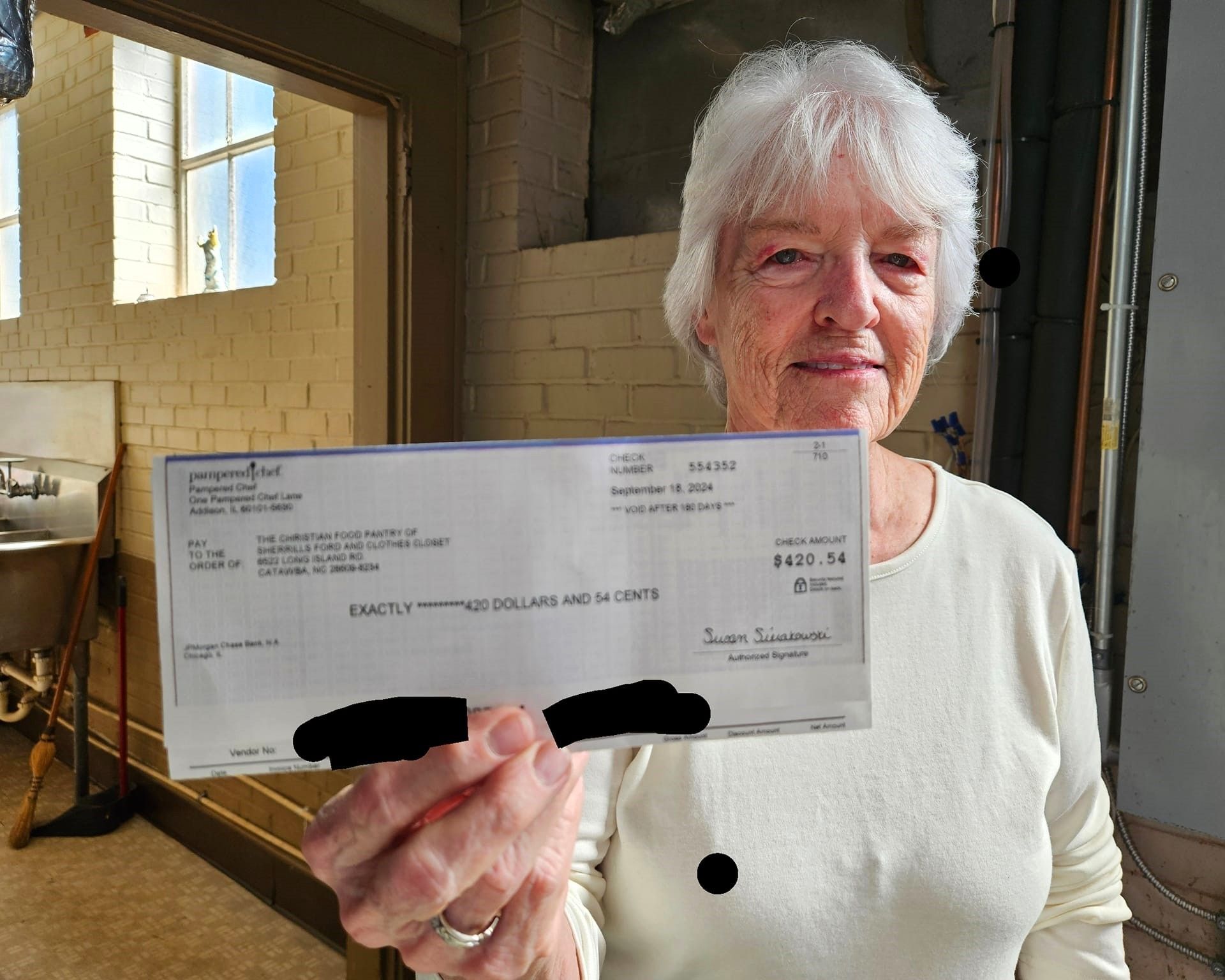 An woman is holding a donation check in her hand.