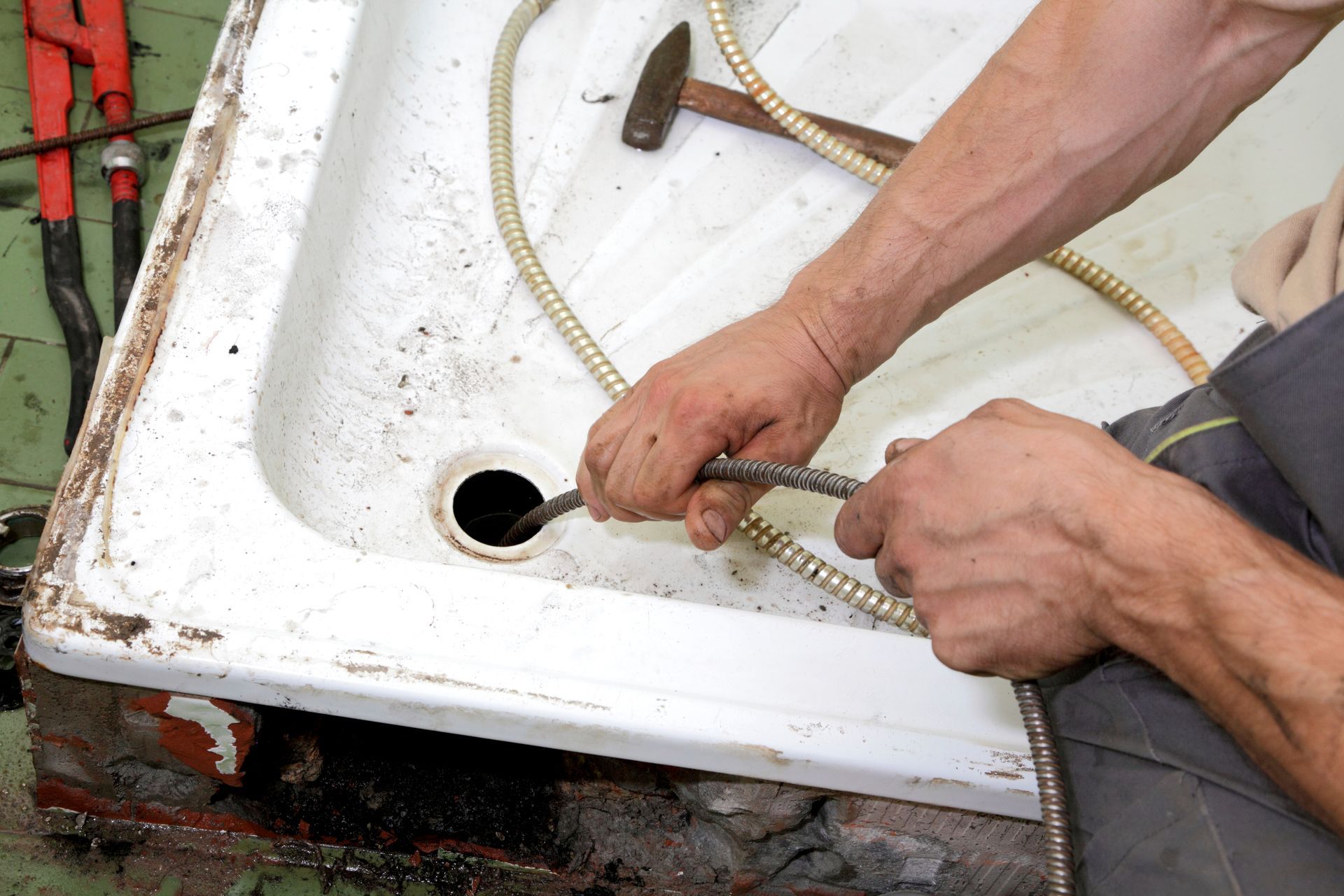 A man is using a hose to drain a shower stall.