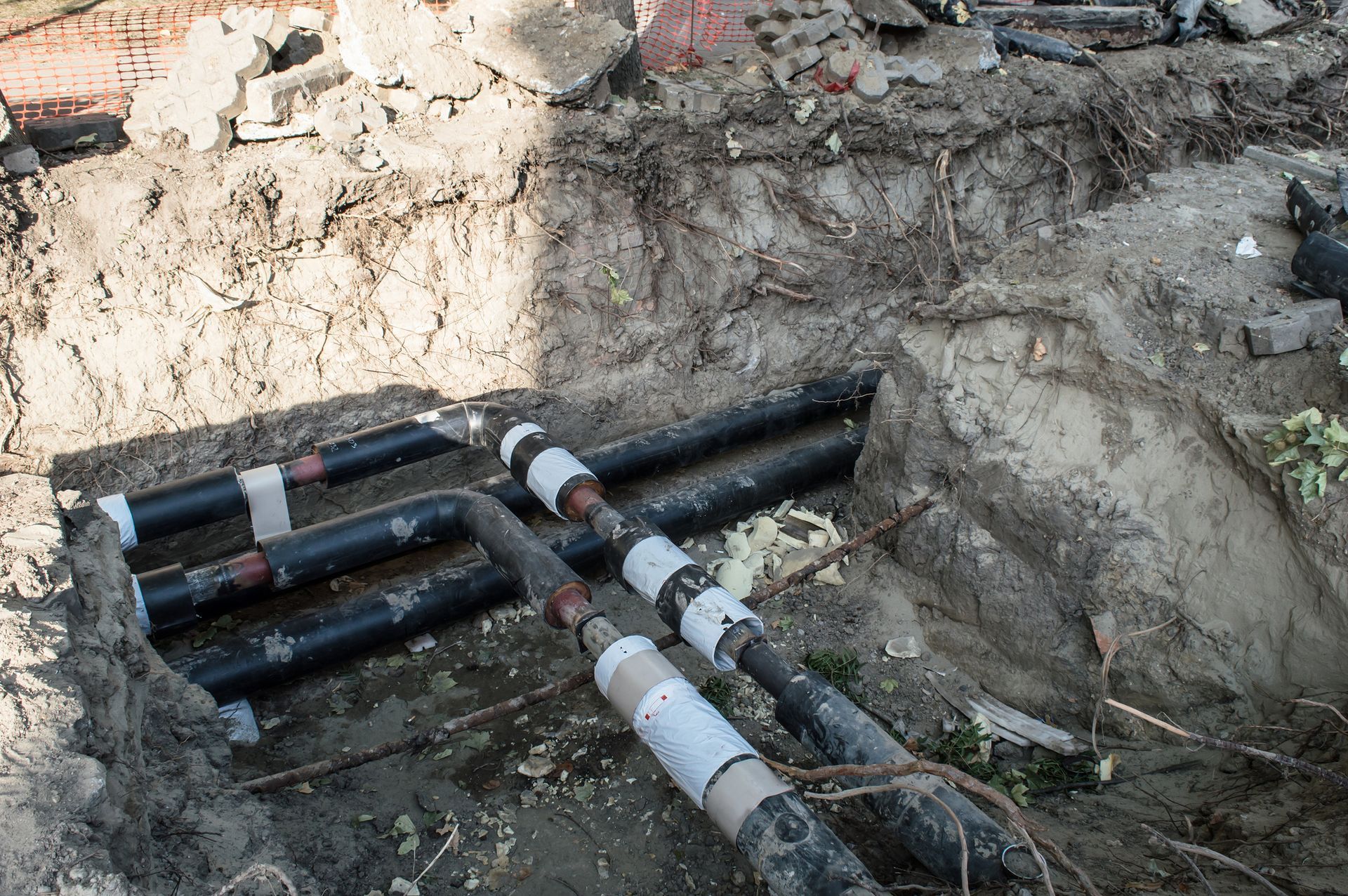 A bunch of pipes are laying in the dirt.