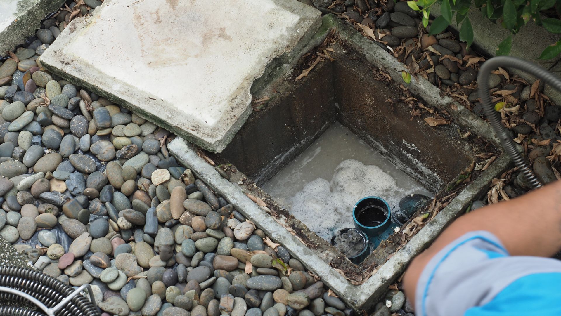 A person is cleaning a drain with a hose.