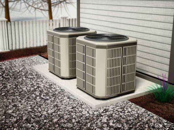 Two air conditioners are sitting outside of a house.