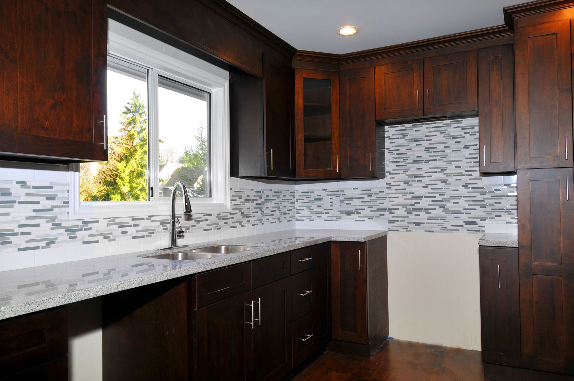 A kitchen with wooden cabinets, granite countertops, a sink, and a window.