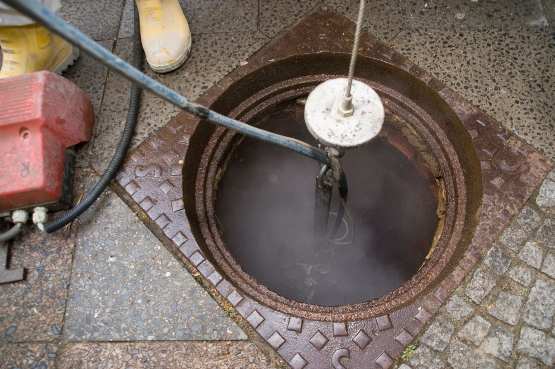 A manhole cover is being cleaned with a machine.